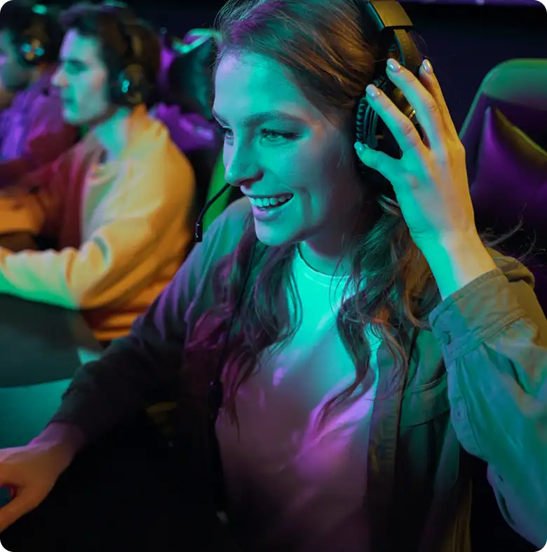 Glimlachende vrouwelijke gamer met een headset op in kleurrijke neonverlichting tijdens een online gamesessie.
